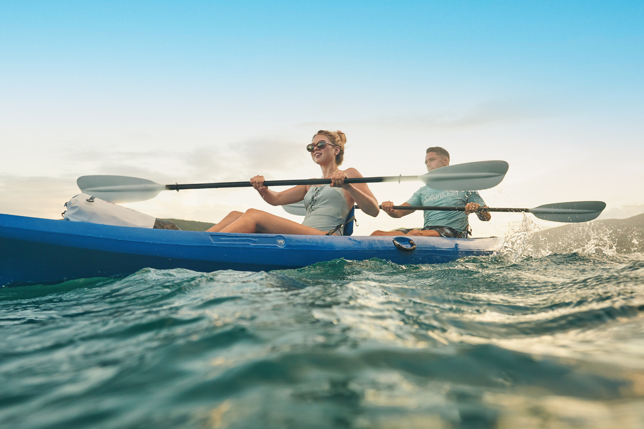 man and woman kayak in tropical water